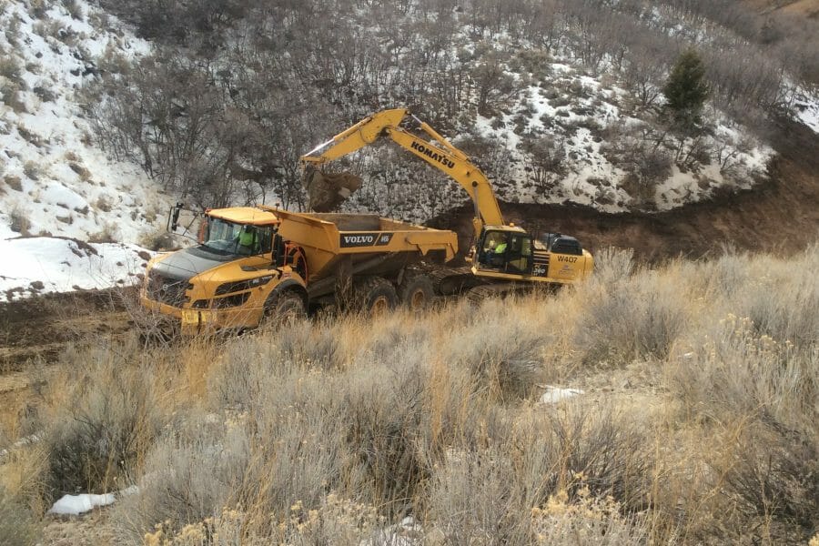 Excavator Digging on Snowy Hillside