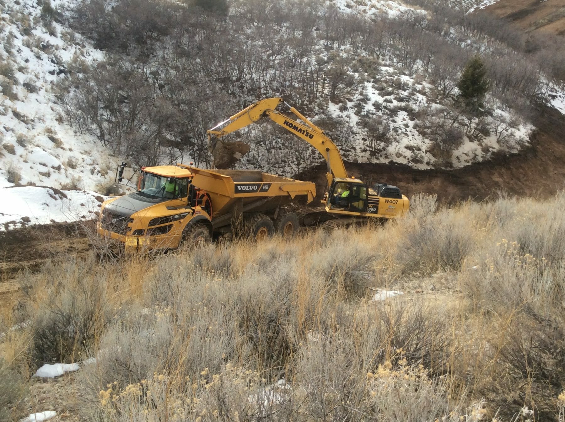 Excavator Digging on Snowy Hillside